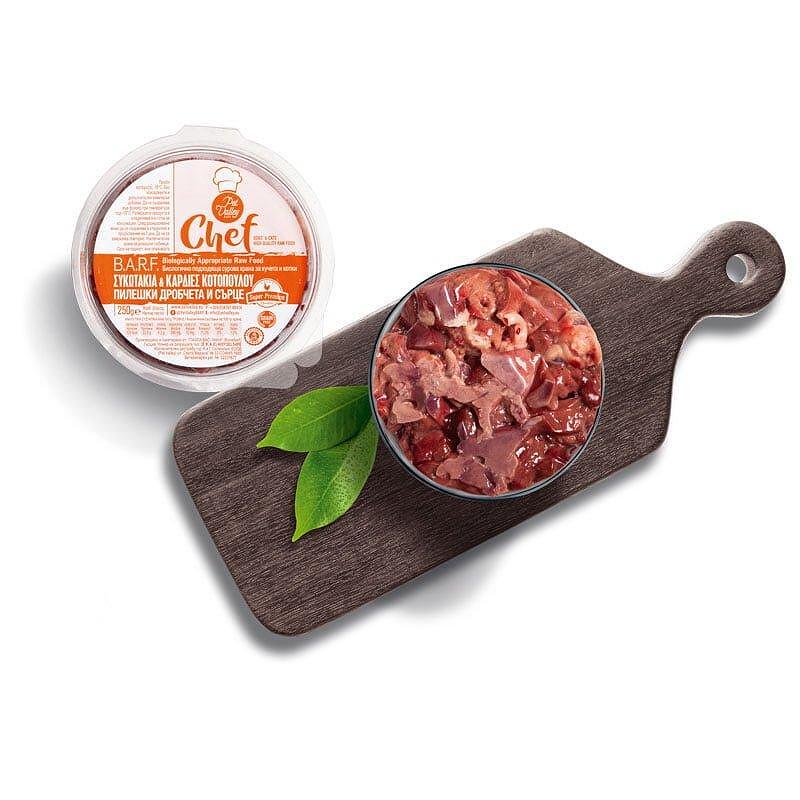 BoneBarf chicken hearts and liver, nutritious pet food in bowl with green leaves on wooden board.