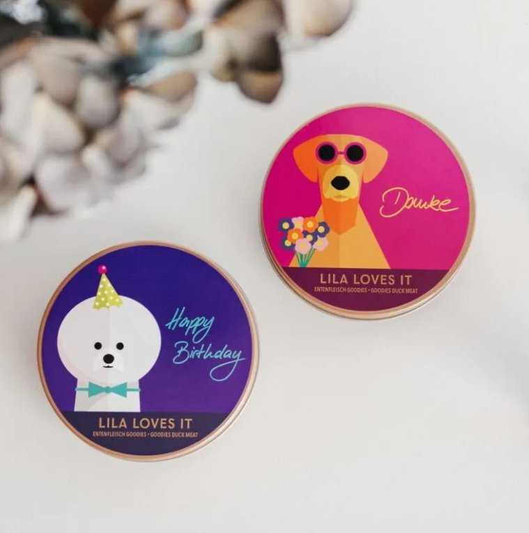 Colorful gift tins from LILA LOVES IT for pets, featuring a birthday theme and a dog named Duke.