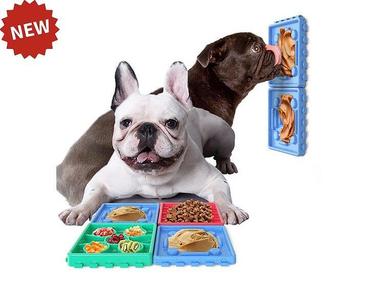 Два кучета, играещи с подложка за бавно хранене, с различни видове храна и нова играчка на стената.